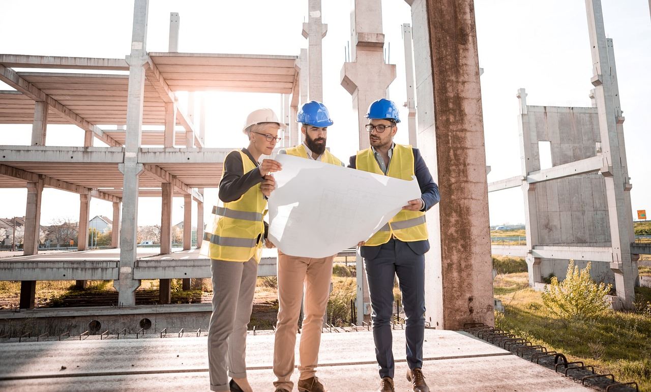 People in hard hats standing looking at plans at construction site